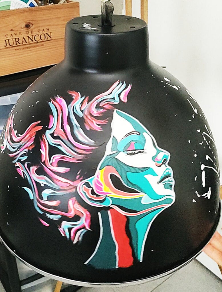 Premier lustre recto pour l'exposition çafaitdeslustres, un visage féminin coloré abstrait, cheveux au vent peint à l'acrylique sur fond noir.